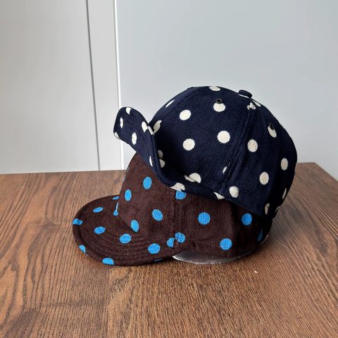 Navy polka-dot corduroy caps stacked on a table