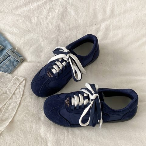 Navy suede-look lace-up trainers on a white rug